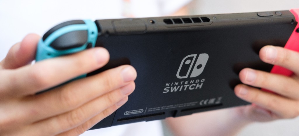 Person hÃ¤lt eine Nintendo Switch in der Hand.