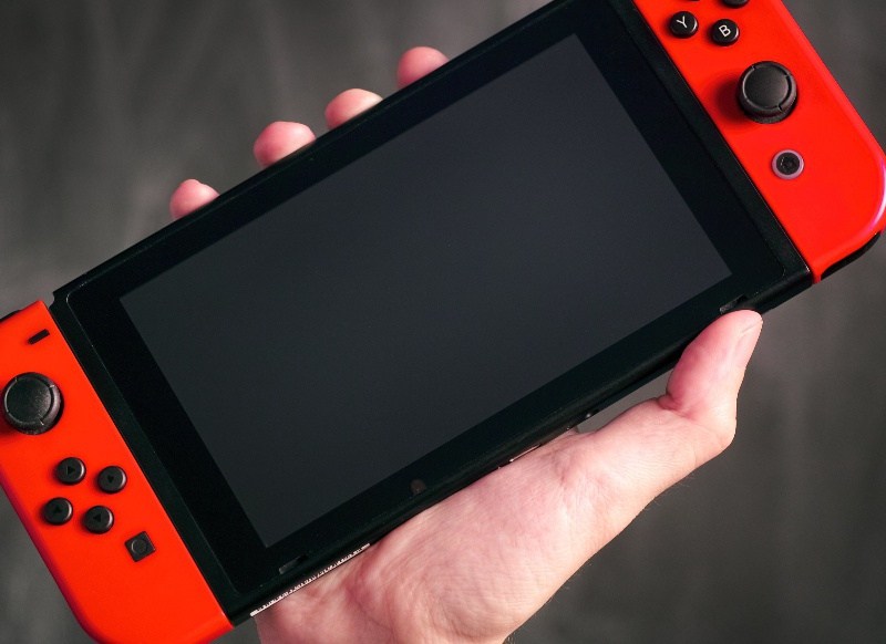 Eine Hand hält die Nintendo Switch in die Luft