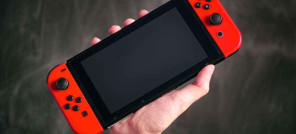 Eine Hand hÃ¤lt die Nintendo Switch in die Luft